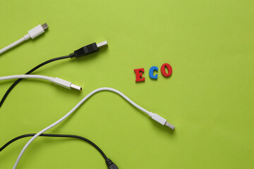 Different usb cables and word eco on green background. Eco concept. Top view