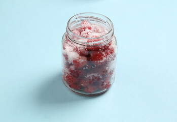 Glass Jar of raspberries with sugar on a blue background
