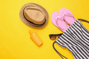 Beach bag with beach accessories on a yellow background. Top view. Flat lay