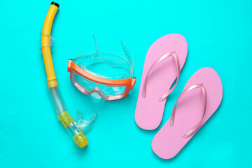 Diving mask and snorkel with flip flops on a turquoise background. Top view