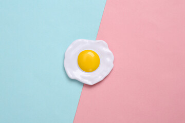 Plastic scrambled eggs on a blue-pink pastel background. Top view. Minimal food concept