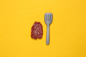 Plastic chop meat and fork on yellow background. Top view. Minimal food concept