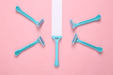 Blue razors on a pink background with a white stripe. Personal care concept. Minimal layout