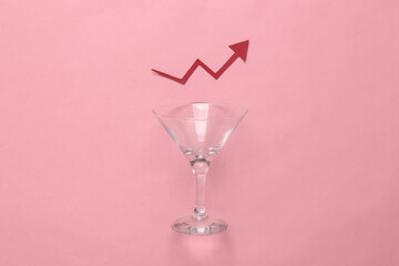 Empty cocktail glass with growth bar on pink background. Alcohol consumption statistics