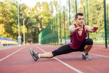 Athletic muscular man warming up before training at the stadium. Healthy lifestyle