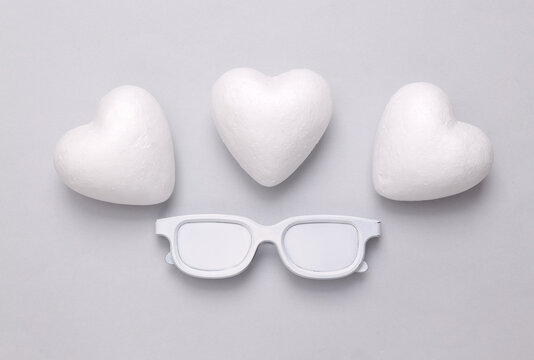 Love layout. White painted glasses and hearts on a gray background