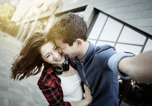 Selfie portrait of a cheerful funny couple in love. A couple is fooling around outdoors. Love concept