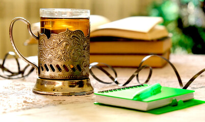 Still life with vintage glass in metal  rusty cup holder and book