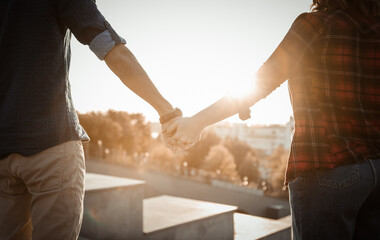 Young couple of lovers hold hands at sunrise. Spending time together. Love concept