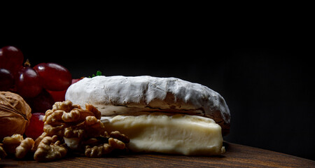 A circle of camembert cheese lies on a wooden board.