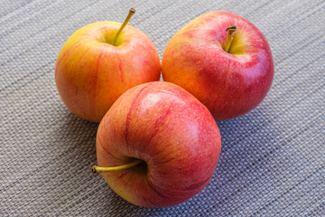 Three red Royal Gala apples are on the table. Popular all-season fruits available. Royal Gala bred by breeders by crossing the varieties Cox Orange Pippin and Golden Delicious