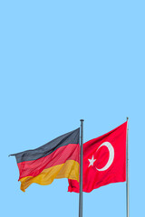 Cover page with national black red yellow flag of Germany and red Turkish flag with white crescent moon and star at blue sky background with copy space. Concept of nationality, citizenship patriotism.