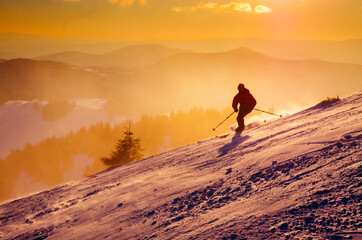 Skier have fun in mountains, beautiful sunset light in background. Ski resort, winter sport