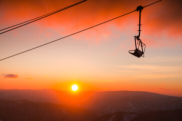 Ski lift cabine in ski resort. Sunrise light in background. Orange edit space for your montage.