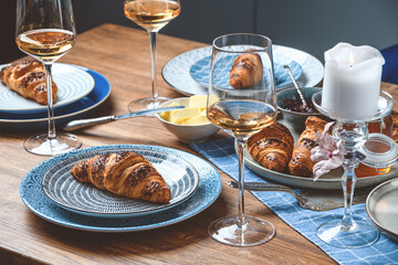 croissants with butter and wine on a wooden table.