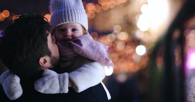 happy toddler baby girl laughing in father's hands during the walk in winter city