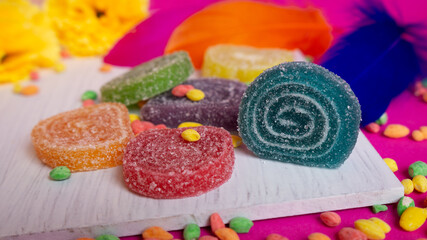 Delicious colorful round jelly candies on a white wooden plate. Close up tasty sugar candy multicolored.