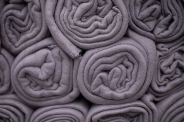  Gray cozy blankets rolled up in rolls are displayed in shop window.Сoncept of shopping for home. Leisure goods. Textile background. Softness and comfort. Warmth and comfort.
