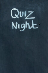 Quiz night chalkboard background sign advertising a trivia knowledge event on a black wood blackboard, stock photo image with copy space