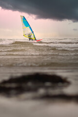 Man windsurfing under dramatic cloudy skies at Silver strand beach in Galway, Ireland 