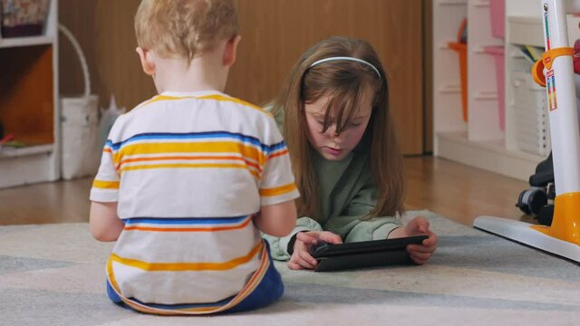 Sister and brother with gadgets on the floor