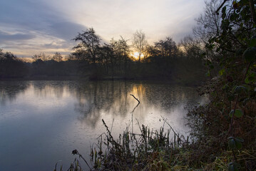 Weak winter sun rises over Mill Lakes on a December morning.