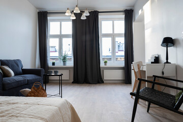 Interior of living room with sofa and armchair with big window. Loft apartment with cozy style in hotel.