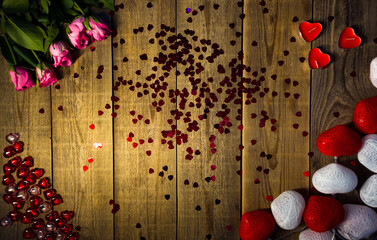 Festive design made of heart shaped decorations and tender pink roses lying on wooden table filmed from above. Preparing for making proposal and celebrating engagement. Making surprise for a soul mate