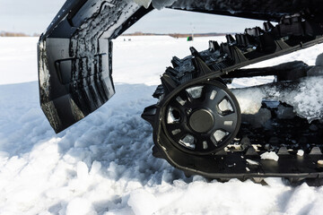 Detail of the rear of a snowmobile with wheel and mudguard. The mechanism of a large machine for...