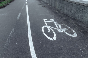 Bicycle lane. Bicycle lane sign on asphalt. Dirty sidewalk with white bike path sign