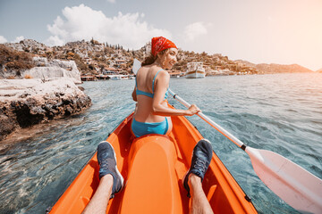 Happy girl is rowing on a double sea kayak with her friend near Kekova island with view of Simena Castle and Kaleucagiz village in Turkey. Outdoor recreation and exploration. Travel as a lifestyle