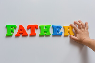 The word FATHER is made of colored magnetic letters typed by a child's hand. Family Day.