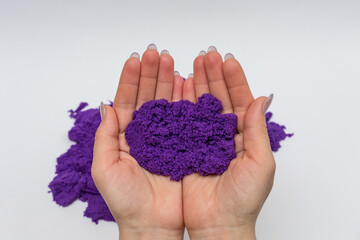 Purple kinetic sand on women's palms.