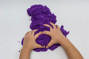 The hands of a small child playing with kinetic sand.