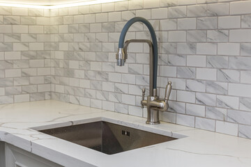 A water tap and a rectangular sink in the kitchen room.