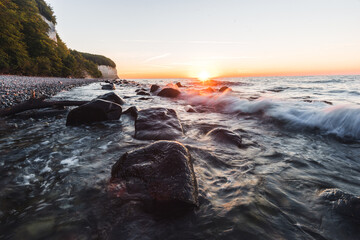 Sonnenaufgang am Meer an den Kreidefelsen auf der Insel Rügen mit Steinen und Wellen