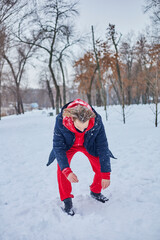 a young happy man is having fun in a winter park, throwing snow, it is cold in his hands, the emissions are off scale.