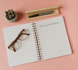 Bonnes résolutions pour la nouvelle année dans un carnet à spirale ouvert avec lunettes, stylo...