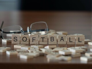 softball concept represented by wooden letter tiles on a wooden table with glasses and a book