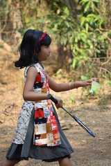 A girl kid is giving service during playing badminton holding racket and shuttlecock or cork in her hands