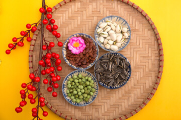 Tet Holiday, Lunar new year, chinese new year concept . Dried sunflower, lotus, watermelon and pumkin seeds top view isolated on yellow. Tet snacks