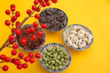 Tet Holiday, Lunar new year, chinese new year concept . Dried sunflower, lotus, watermelon and pumkin seeds top view isolated on yellow. Tet snacks