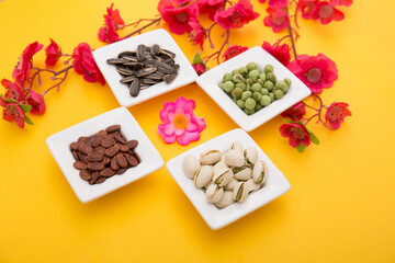 Tet Holiday, Lunar new year, chinese new year concept . Dried sunflower, lotus, watermelon and pumkin seeds top view isolated on yellow. Tet snacks