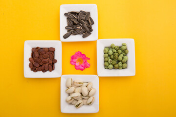 Tet Holiday, Lunar new year, chinese new year concept . Dried sunflower, lotus, watermelon and pumkin seeds top view isolated on yellow. Tet snacks