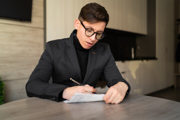 young man portrait, online webinar training coach, sitting at the table writing down ideas, paper work, businessman working at home