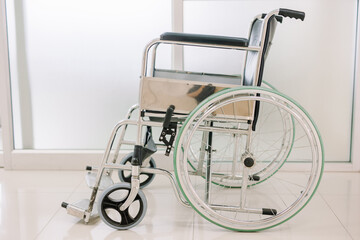 A wheelchair is parked in the hospital with no one sitting. wheelchair for moving patients who cannot walk