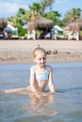 Little girl playing on the beach by the sea