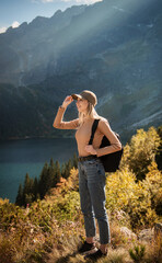 Wanderlust and travel concept. Stylish traveler girl in cap looking in front of mountain on sunny day