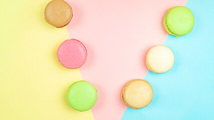 Multicolored macaroon cakes on colored bedding background with copy space
