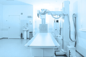 X-ray department in modern hospital. Radiology room with scan machine with empty bed. Technician adjusting an x-ray machine. Scanning chest, heart, lungs in modern clinic office